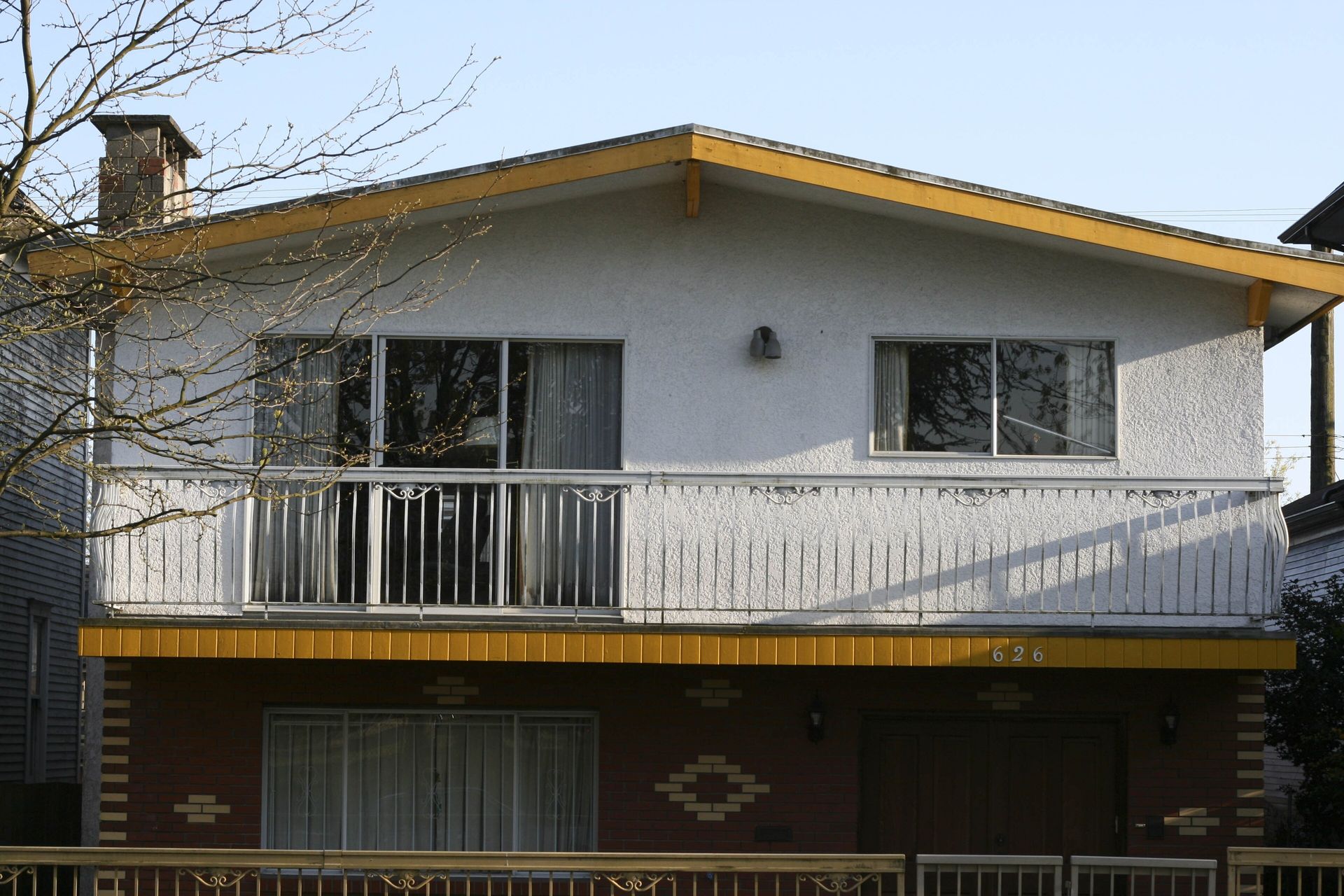 Front of a Vancouver Special house with a full-width balcony