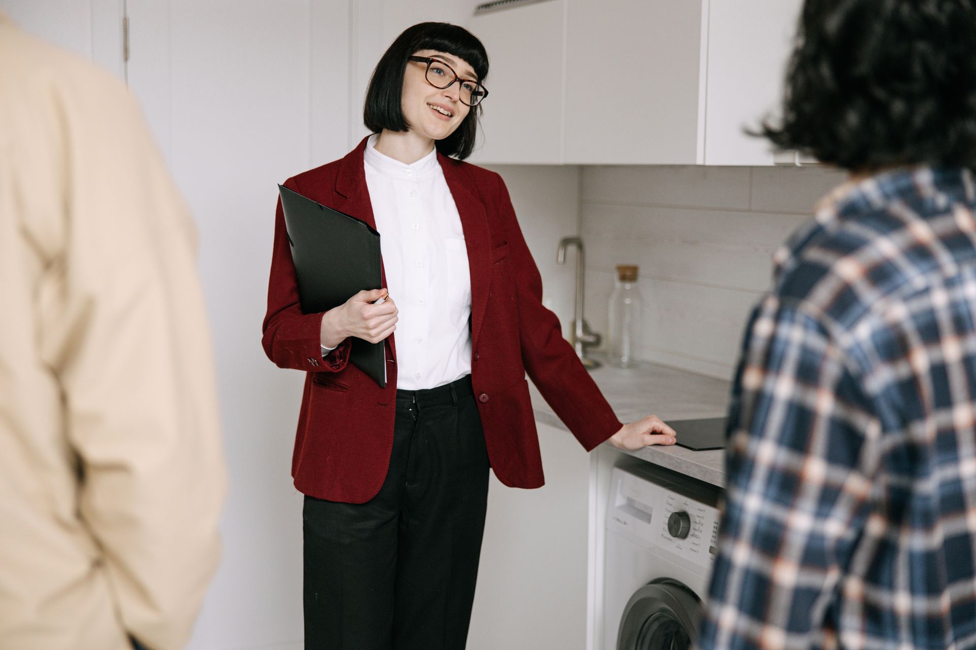 An agent showing buyers around an apartment kitchen; illustrative stock photograph